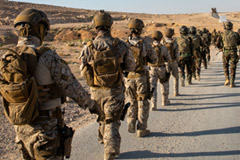 Soldiers wearing camouflage march down a desert road