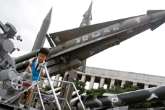 A child plays with old weapons displayed for visitors at the Korean War Memorial Museum in Seoul, Aug 11, 2011