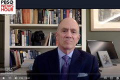 screenshot of Joel Brenner with bookcase behind him being interviewed