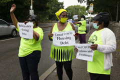 Annie Gordon, left, Gabrielle Rene, center, and Jenny Clark, right, rally for protection from evictions Saturday, June 27, 2020, in the Mattapan neighborhood of Boston. Massachusetts' tenant eviction moratorium is slated to expire in mid-August. (AP Photo/Michael Dwyer)