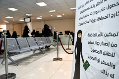 Saudi women wait with their forms to apply for new passports on Aug. 29 at the Immigration and Passports Center in the capital, Riyadh, with a sign on the right reading out the details of a royal decree allowing women, age 21 and older, to obtain passports for themselves and for children in their custody, without seeking the approval of their “guardians” — fathers, husbands or other male relatives. (Fayez Nureldine/Afp Via Getty Images)